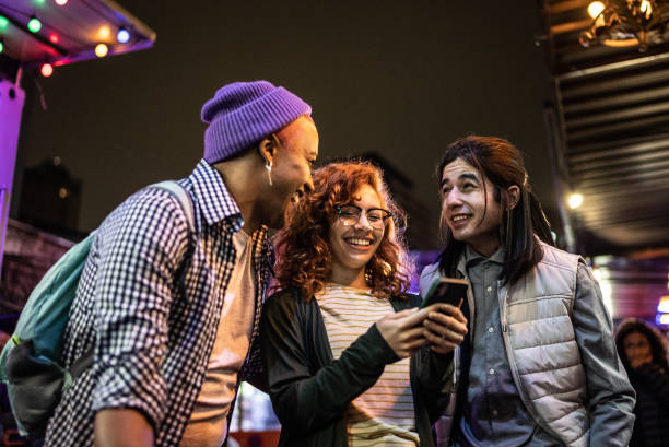 istock Friends using mobile phone at festival by the night 1415631173