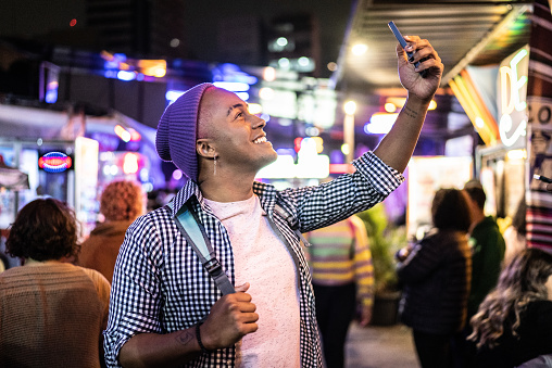 Young man taking selfies or filming outdoors at food truck festival