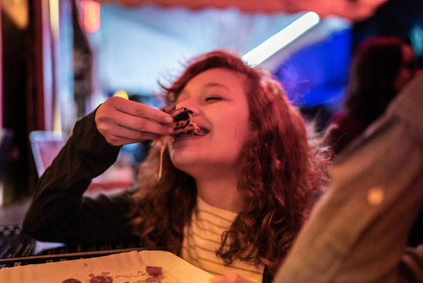 Young woman eating pizza outdoors at night