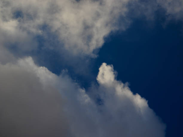istock thin white cumulus cloud with parts shaded and others illuminated by sunbeams, floating under a blue sky. 1415634258