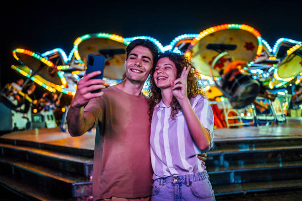 istock Young couple taking a selfie at the funfair 1415634276