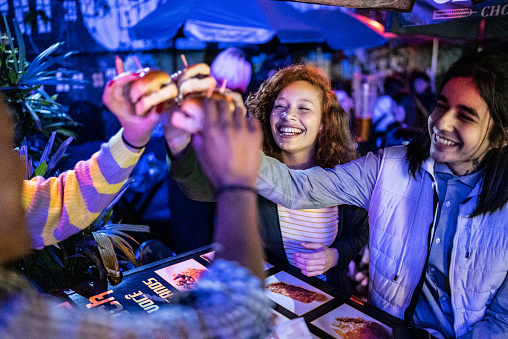 Friends toasting with hamburguers outdoors at night