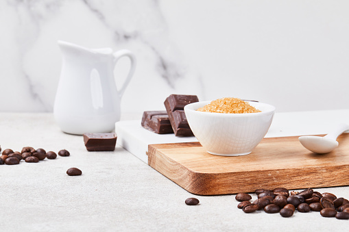 Roasted coffee beans on a white modern kitchen table top, with chocolate and brown sugar