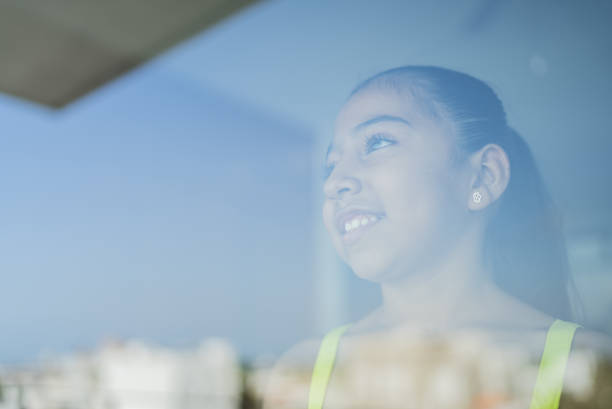 Girl contemplating looking through window at home