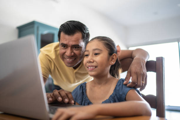 istock Father helping daughter studying on the laptop at home 1415638771