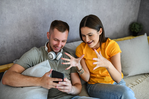 Smiling Couple Looking At Cute Animal Pics Online On Smartphone
