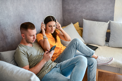 Cute Couple Making New Playlists With Smartphone And Headphones