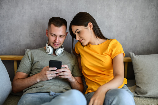 Male And Female Looking At New Items To Buy Online Via Smartphone