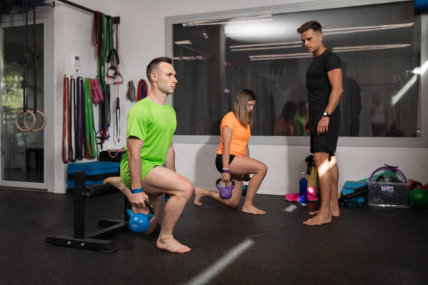 istock Two trainees woman and man doing some lunges with weight 1415639956