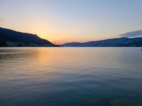 Sunset at Ägerisee (Lake Aegeri) in the Canton of Zug, Switzerland. The two municipalities along its shore are Oberägeri and Unterägeri. The image shows the lakeside with some stones captured during springtime.