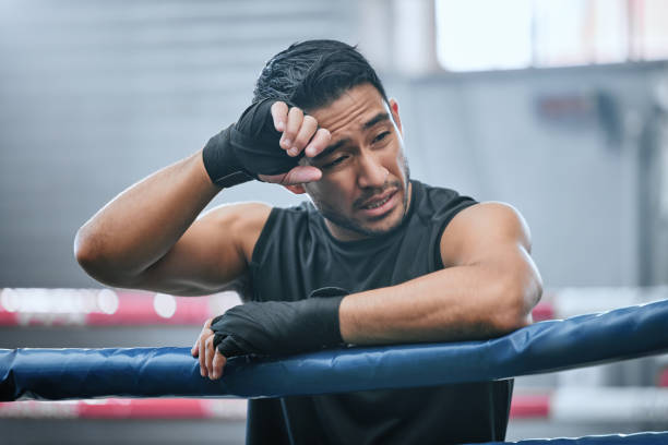 istock Fit, active or healthy boxing man feeling tired, hot and wiping sweat after workout, training or exercise in ring. Sporty, athletic or strong boxer upset after losing kickboxing fight or sports match 1415642765
