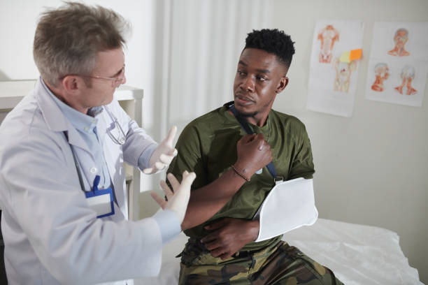 un médecin parle à un militaire avec le bras cassé - clothing professional occupation medical occupation doctor photos et images de collection