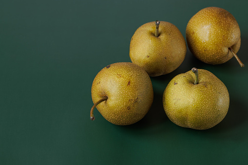 Istanbul, Turkey-August 18, 2022: Four asian pears on a dark green background. Shot with Canon EOS R5.