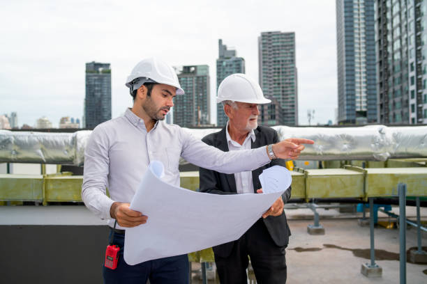 istock Close up scene with two engineers or technicians talk together and stay on rooftop of construction site. 1415649293