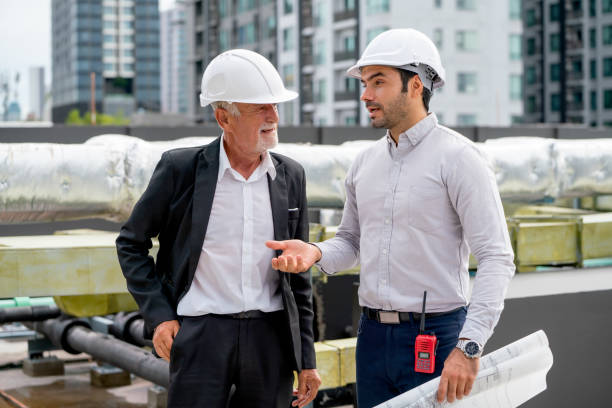 istock Close up scene with two engineers or technicians talk together and stay on rooftop of construction site. 1415649339
