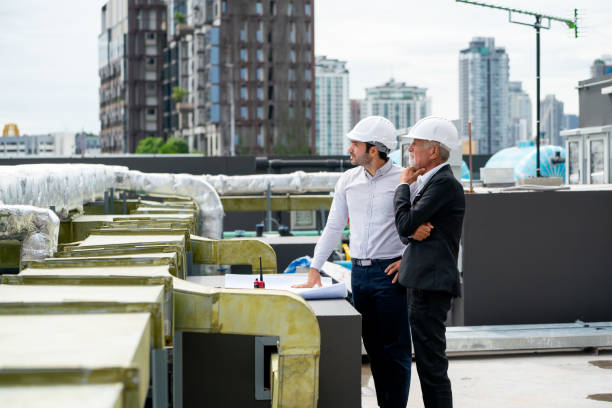 istock Senior engineer man stand with action of thinking and work with young technician with stand in front of air vent line in construction site. 1415649357