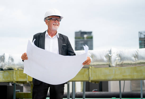 istock Senior professional engineer or technician use building drawing plan to guide for working in construction site. 1415650912