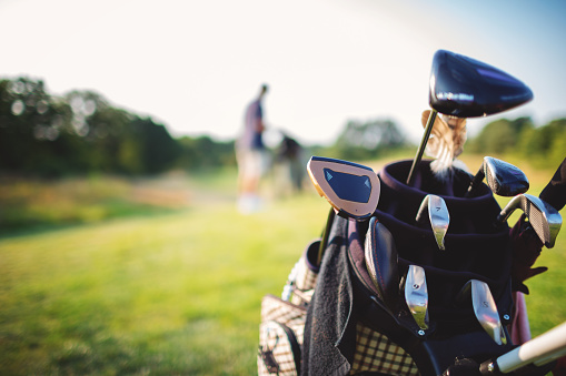 Golf bag with clubs on the golf course in summer.