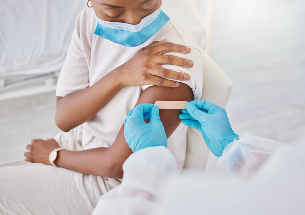 clinic, mask and nurse puts plaster on patient after injection. medical worker covering arm with care after checking and testing person in mobile lab. nursing, wellness and adult healthcare or exam. - telephone doctor medical exam healthcare and medicine imagens e fotografias de stock