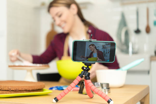 istock Young woman making a cake and filming a tutorial with her smartphone 1415653298