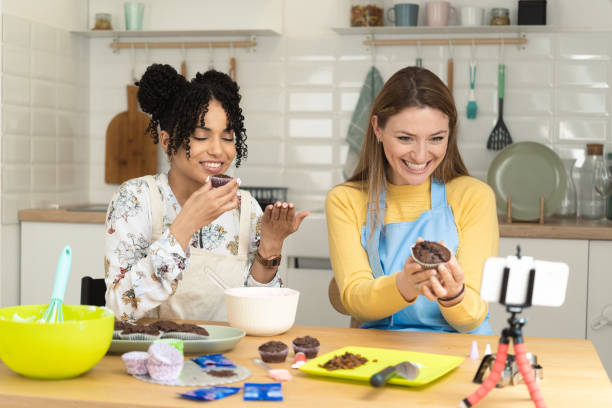 istock Two happy girls making an online video tutorial for making muffins 1415653407