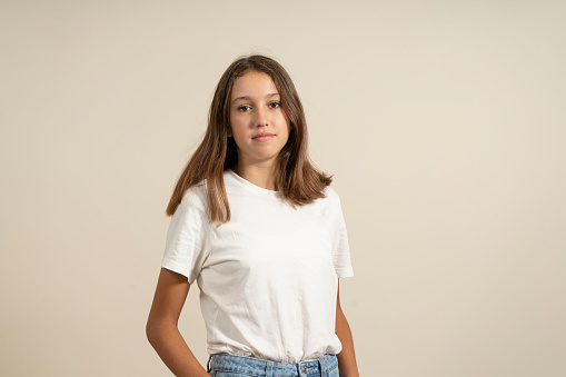 Portrait of a young European woman with healthy clean skin and brown eyes wearing a casual top looking at the camera with a serious expression. Spanish female model with loose hair