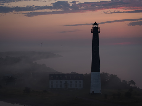 lighthouse on a foggy morning, drone point of view, sunrise.