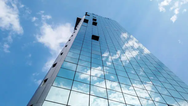 Timelapse of a modern glass building reflecting clouds and blue sky