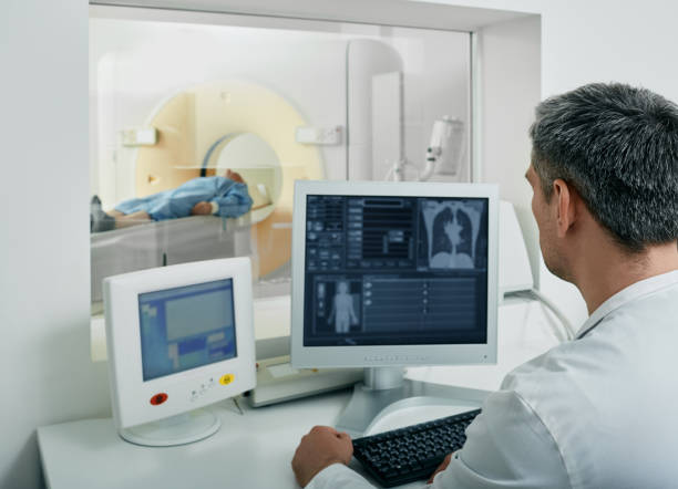 medico radiologo che esegue la scansione tc per i polmoni del corpo del paziente dalla sala di controllo. tomografia computerizzata - radiologist computer doctor mri scan foto e immagini stock