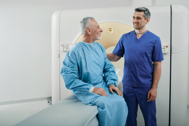 röntgenologe, der mit einem männlichen patienten in der radiologischen abteilung des krankenhauses spricht, bevor der ct-scan durchgeführt wird. computertomographie - mri scanner mri scan patient doctor stock-fotos und bilder
