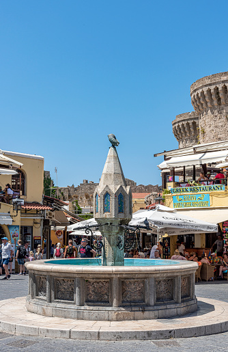 Rhodes Island, Greece - May 23, 2022: Tourists on the historic Hippocrates Square, in the Old Town center of the island of Rhodes, Greece. Hippocrates Fountain.