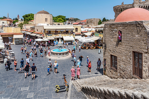Rhodes Island, Greece - May 27, 2022: Tourists on the historic Hippocrates Square, in the Old Town center of the island of Rhodes, Greece. Hippocrates Fountain.