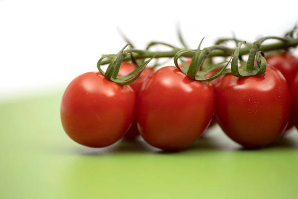 Fresh cherry tomatoes on green professional chopping board