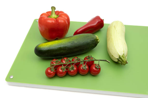 Red peppers, squash, zucchini and cherry tomatoes on green professional chopping board - isolated on white background 4