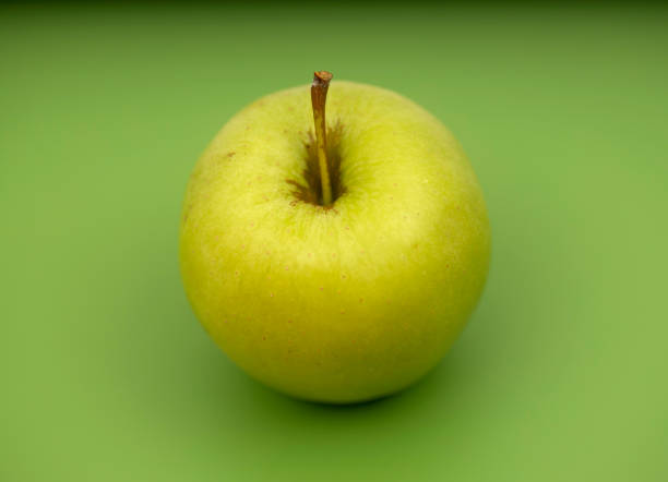 istock Yellow apple on green background 1415669500