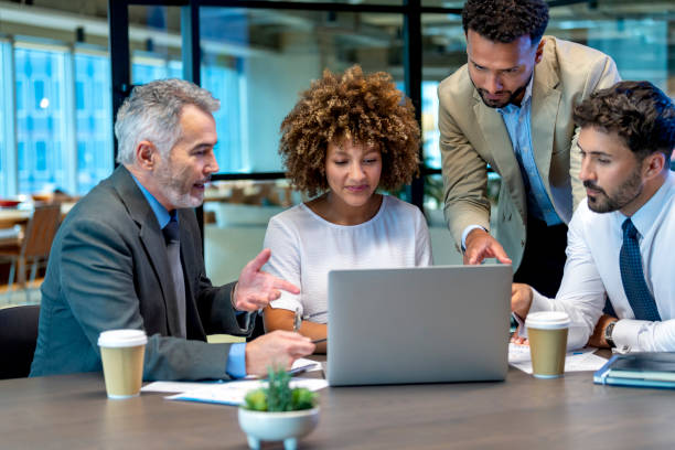 istock Four business people working on a laptop computer in an office. 1415670108
