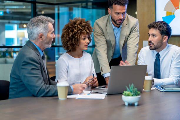 istock Four business people working on a laptop computer in an office. 1415670111
