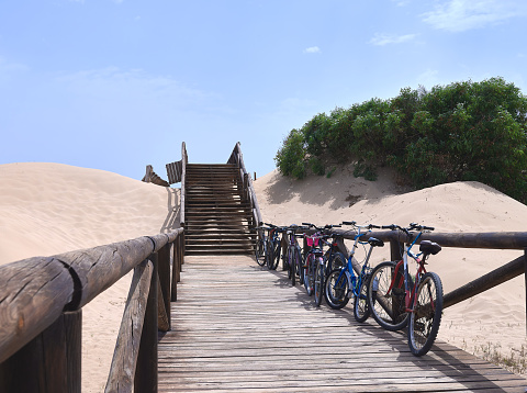 detail of bicycles parked on a wooden walkway towards the beach