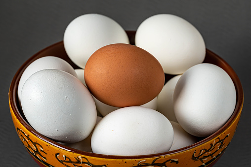 Fresh eggs in bowl on grey background