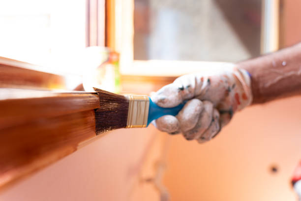 Senior man applying protective varnish on a wooden window Caucasian ethnicity Senior man applying protective varnish on a wooden window house painting service stock pictures, royalty-free photos & images