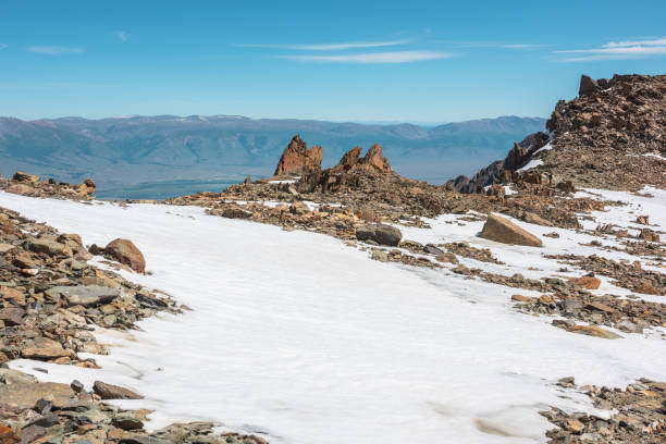 Scenic mountain landscape with old rocks and stones among snow in sunlight. Awesome alpine scenery with stone outliers on high mountain under blue sky in sunny day. Sharp rocks at very high altitude. paisaje escénico de montaña con rocas y piedras antiguas entre la nieve a la luz del sol. impresionante paisaje alpino con valores atípicos de piedra en alta montaña bajo el cielo azul en un día soleado. rocas afiladas a muy gran altitud.
