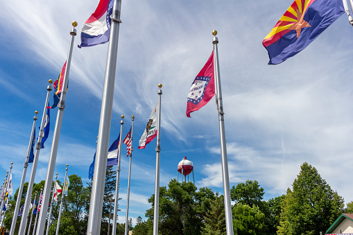 Pequot Lakes, Minnesota, USA - August 11, 2022: Daytime view of various state flags lining a city park in the town of Pequot Lakes in northern Minnesota.