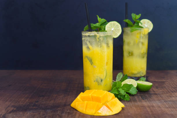 Mango mojito in highball glass with sliced mango on wooden table stock photo