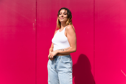 Beautiful modern Maori woman looking at camera with pink background.