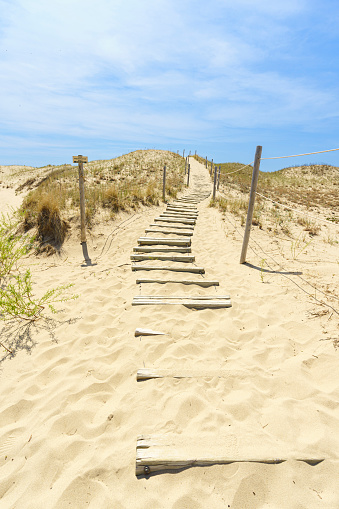 A set of s-curve stairs ascend and sand dune locate in Michigan Sleeping Bear National Lakeshore.  The stairway leads to the blue sky with light white clouds.
