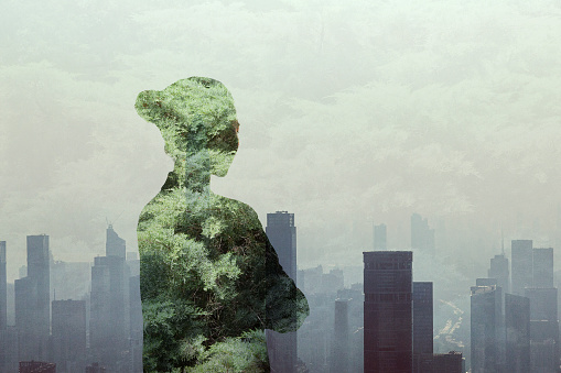 Person standing in contemplation in smog urban city reflection with nature trees