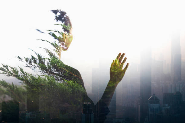 Adult woman person standing waist up rear view with hand in contemplation of social issues in smog urban city reflection with nature trees, composite, multi-layered effect, in silhouette Person standing in contemplation in smog urban city reflection with nature trees better world stock pictures, royalty-free photos & images