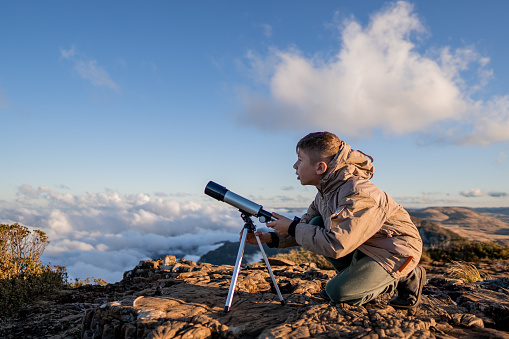 Young explorer high in the mountains with telescope