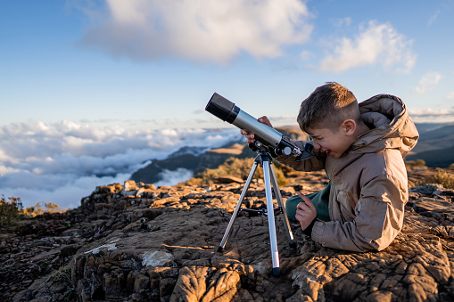 Young explorer high in the mountains with telescope