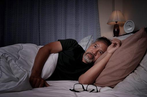 anciano deprimido y estresado acostado en la cama por insomnio photo